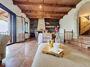 Un ambiente accogliente con camino in pietra, soffitto in legno e zona pranzo con sedie e tavolo.