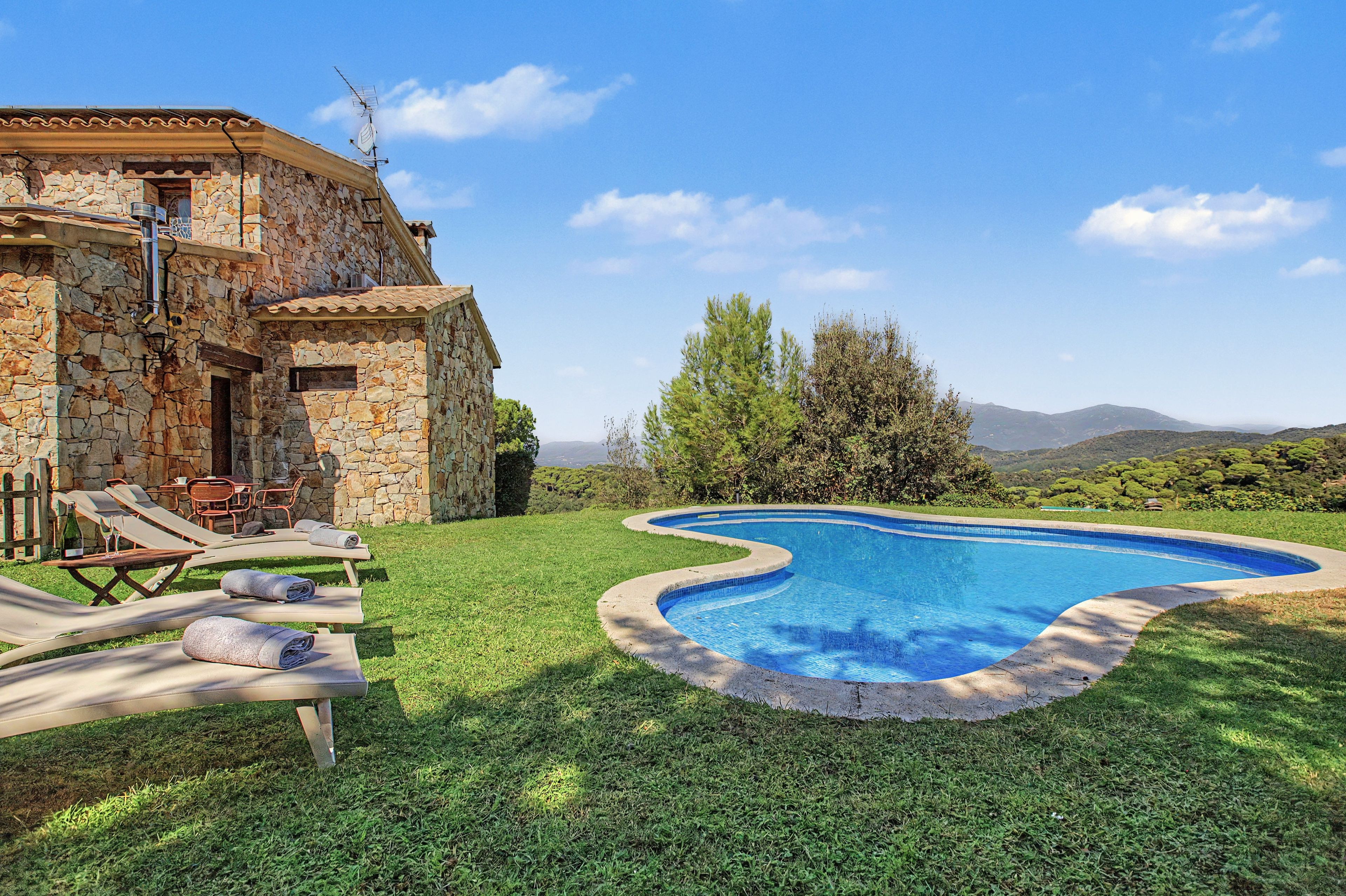 Uma vila de pedra com piscina, área de estar ao ar livre e vista para as colinas.