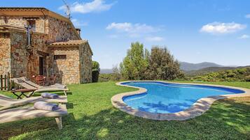 Uma vila de pedra com piscina, área de estar ao ar livre e vista para as colinas.