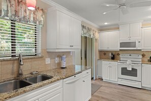 A kitchen with white cabinets, a granite countertop, stainless steel sink, a refrigerator, a microwave, and an oven. - Close to Beach, 2 Balconies, Community Pool (Miramar Beach)