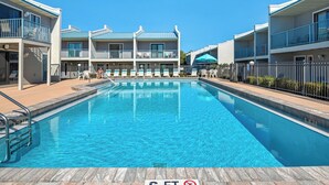A swimming pool with a 'no diving' sign, surrounded by multi-story buildings with balconies and outdoor seating. - Close to Beach, 2 Balconies, Community Pool (Miramar Beach)