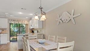 A dining area with a table, chairs, a chandelier, and a decorative starfish on the wall. - Close to Beach, 2 Balconies, Community Pool (Miramar Beach)