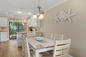 A dining area with a table, chairs, a chandelier, and a decorative starfish on the wall. - Close to Beach, 2 Balconies, Community Pool (Miramar Beach)