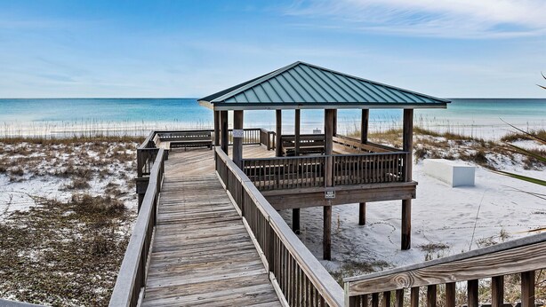 A wooden boardwalk leading to a beach gazebo with a metal roof. - Close to Beach, 2 Balconies, Community Pool (Miramar Beach)
