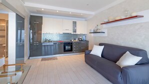 Une cuisine moderne dotée d’appareils électroménagers intégrés, un canapé gris et une table basse en bois.