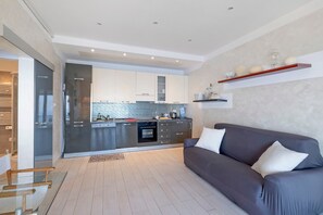 A modern kitchen with integrated appliances, a grey sofa, and a wooden coffee table.