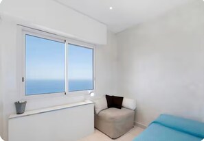 A room with a large window, a radiator, a small ottoman, and a bed. - Loft with Sea View near Monaco (Roquebrune-Cap-Martin)