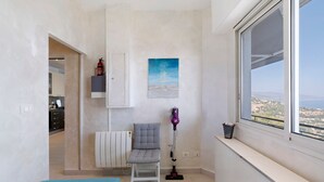 Une pièce comprenant un lit, une chaise, un radiateur, une fenêtre donnant sur un paysage et un tableau accroché au mur.