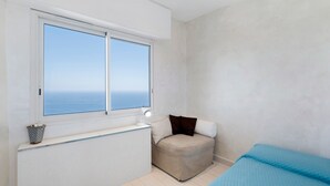 Une chambre avec une fenêtre, une table de chevet, une chaise et un lit.