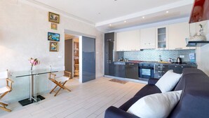 Un salon moderne avec une table à manger en verre, un canapé et une cuisine en arrière-plan.
