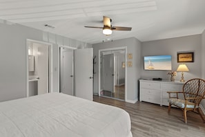 A bedroom with a bed, a ceiling fan, a dresser, a chair, and a painting on the wall. - Steps to the Beach, Private Balconies, Community Pool (Miramar Beach)