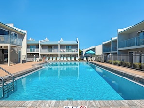 A swimming pool with a 'no diving' sign, surrounded by multi-story buildings with balconies and outdoor seating. - Steps to the Beach, Private Balconies, Community Pool (Miramar Beach)