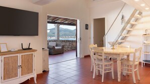 A room with a dining table, chairs, a cabinet, a TV, and a staircase. - Casa Matilde con Patio by Wonderful Italy (Olbia)