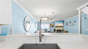 A kitchen with a sink, a mirror, and a view of the living room. - Beach Front Townhome in Miramar Beach (Miramar Beach)