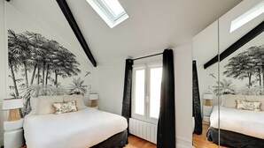 Quarto com cama, janela, espelho e parede com um mural tropical.