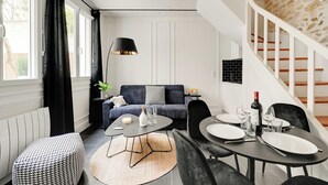 Uma sala de estar moderna com sofá, mesa de jantar e escada.