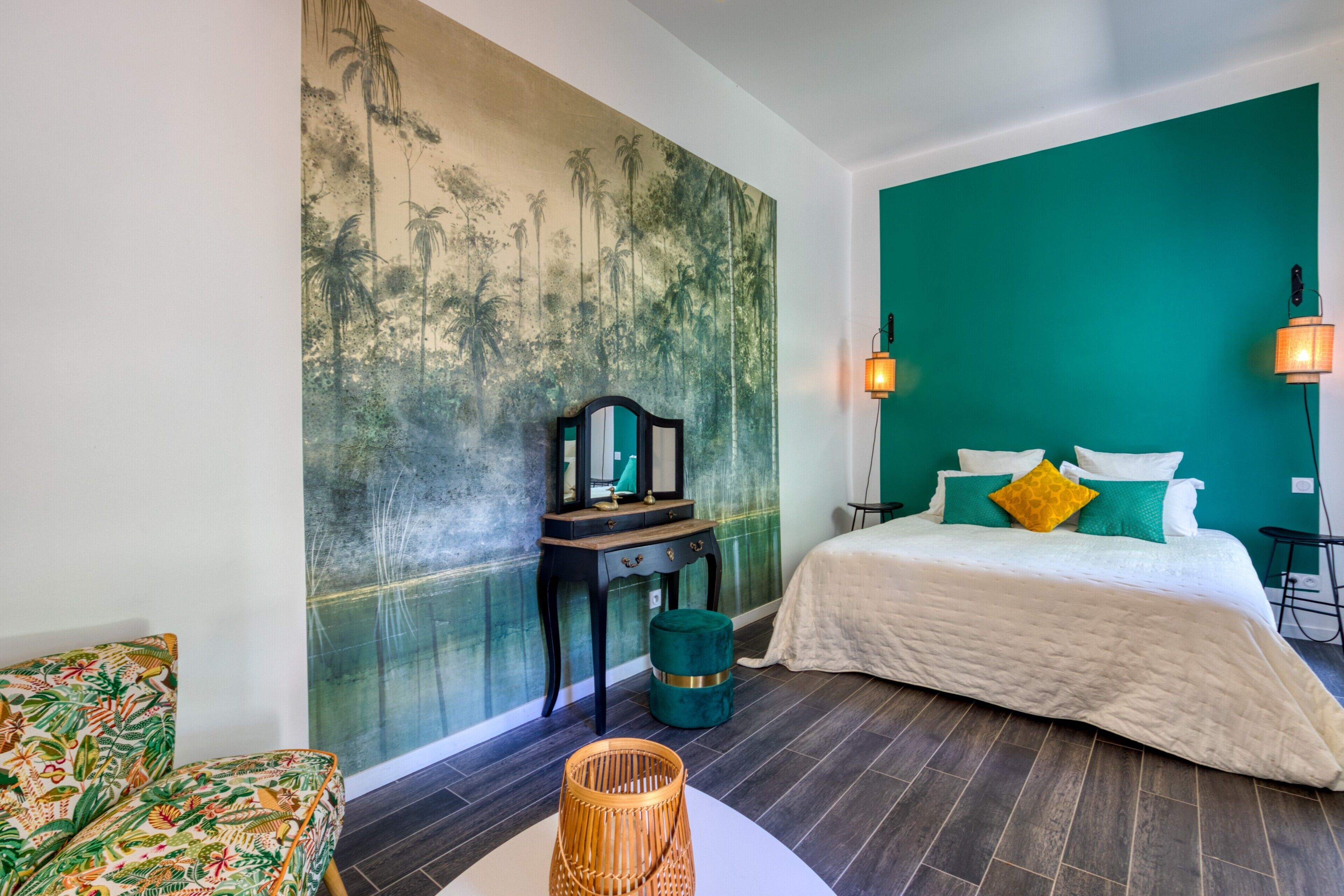 Une pièce comprenant un lit, une table de chevet, une chaise, un mur orné d’un tableau et une lampe.
