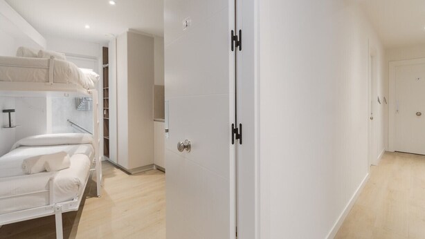 A room with a bunk bed, a wardrobe with black handles, and a door leading to another room. - Txapitela Rooms - Perfect for 2 (Pamplona)