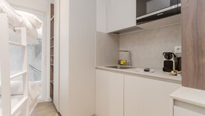 A compact kitchen with white cabinetry, a microwave, a coffee machine, and a small sink. - Txapitela Rooms - Perfect for 2 (Pamplona)