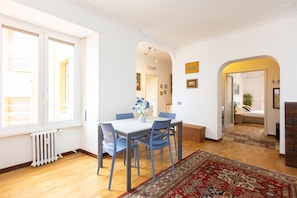 Ein Essbereich mit Tisch, Stühlen, einem Heizkörper und einem Fenster mit Jalousien.