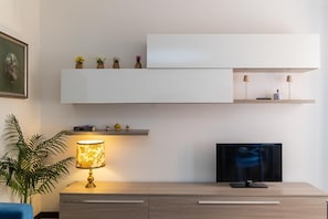 Ein modernes Wohnzimmer mit Fernseher, Lampe und Pflanze.