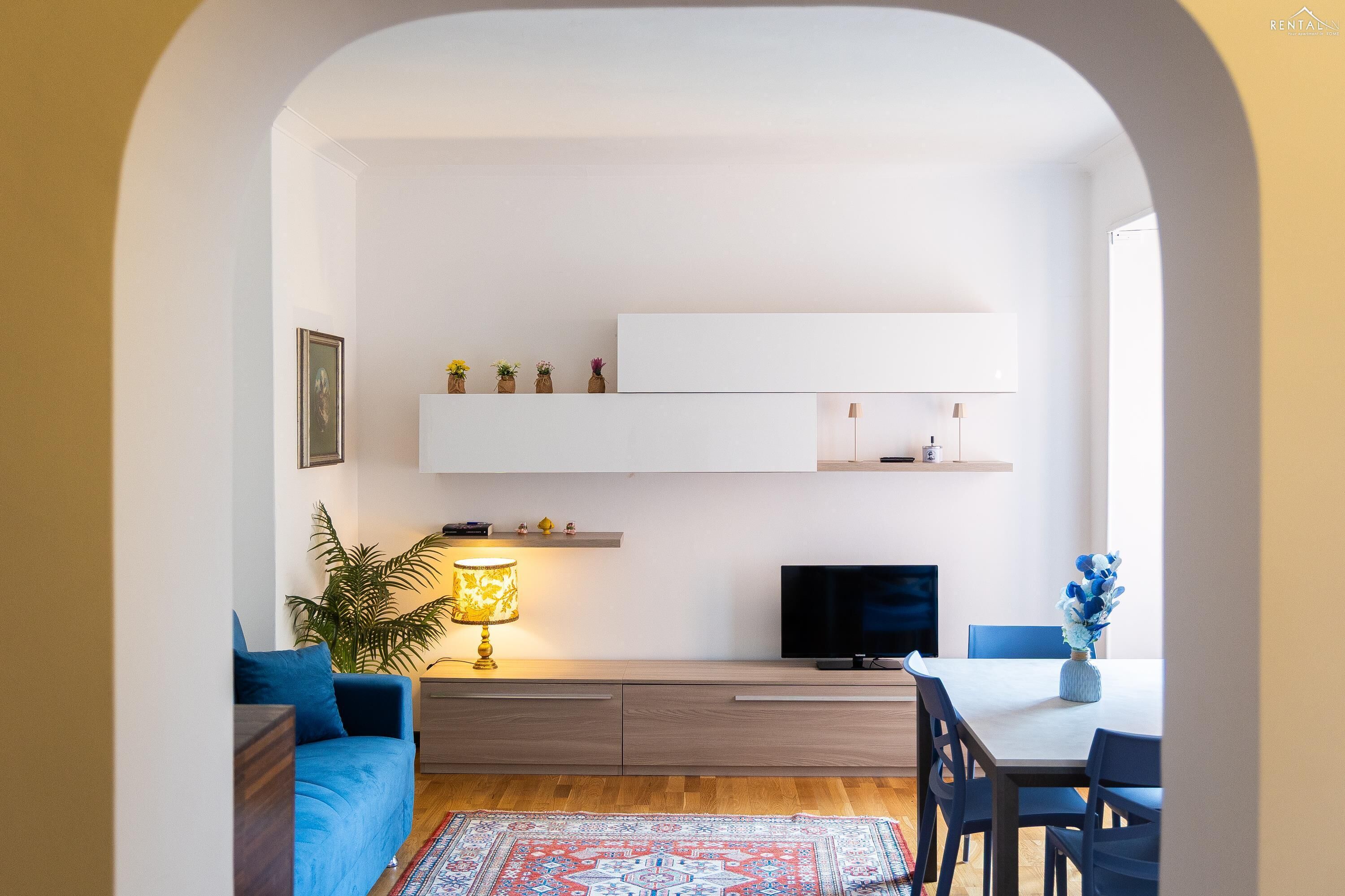 A modern living room with a sofa, TV, and dining table.
