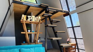A modern interior with a blue sofa, wooden ladder, and a sign reading 'ALPINA'.