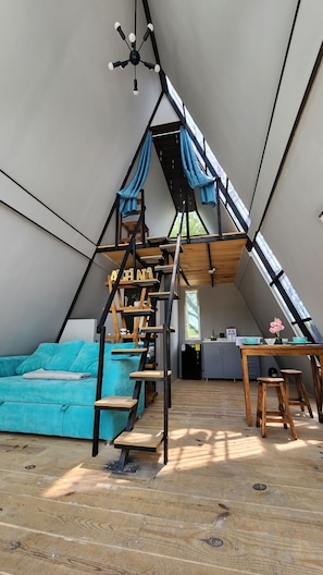 Une piÚce de style loft avec un escalier en bois, un canapé, une table et un coin cuisine.