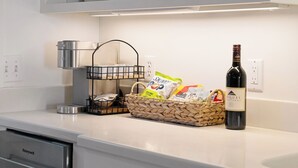 En köksbänk med en vinflaska, en korg med snacks och en kaffebryggare.
