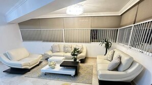 Een moderne woonkamer met een hoekbank, een salontafel en een potplant.