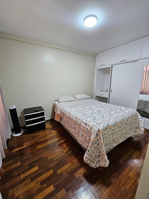 Un dormitorio con cama, armario y un pequeño altavoz negro.