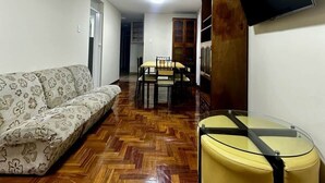 Un salon avec un canapé, une table en verre, un téléviseur et un plancher en bois.