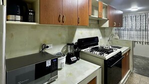 Une cuisine avec des meubles de rangement en bois, une cuisinière, un four à micro-ondes Electrolux et une machine à café.