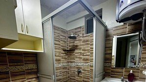 Une salle de bain équipée d’une douche, de toilettes, d’un lavabo et d’un miroir.