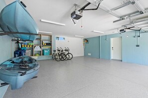 A spacious room with a ceiling-mounted projector, bicycles, and a kayak. - Casa Del Sol | Rooftop Deck, Pool + Ocean Views (Anna Maria)