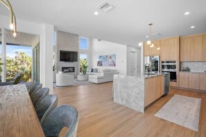 Eine moderne Küche mit Holzschränken, einer zentralen Kochinsel und einem Essbereich mit Tisch und Stühlen.