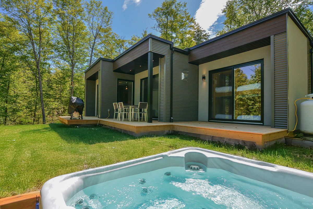 Una casa moderna con jacuzzi, un patio con sillas y una parrilla.