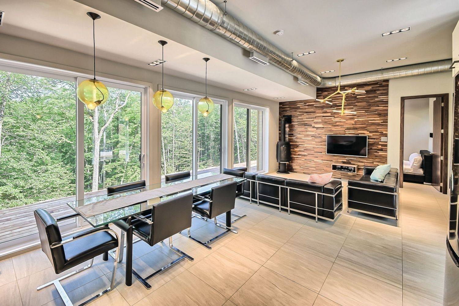 A modern kitchen with a dining area, large windows, and a TV mounted on the wall.
