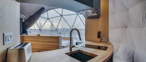 A modern kitchen with a large window, a built-in sink, and a toaster.
