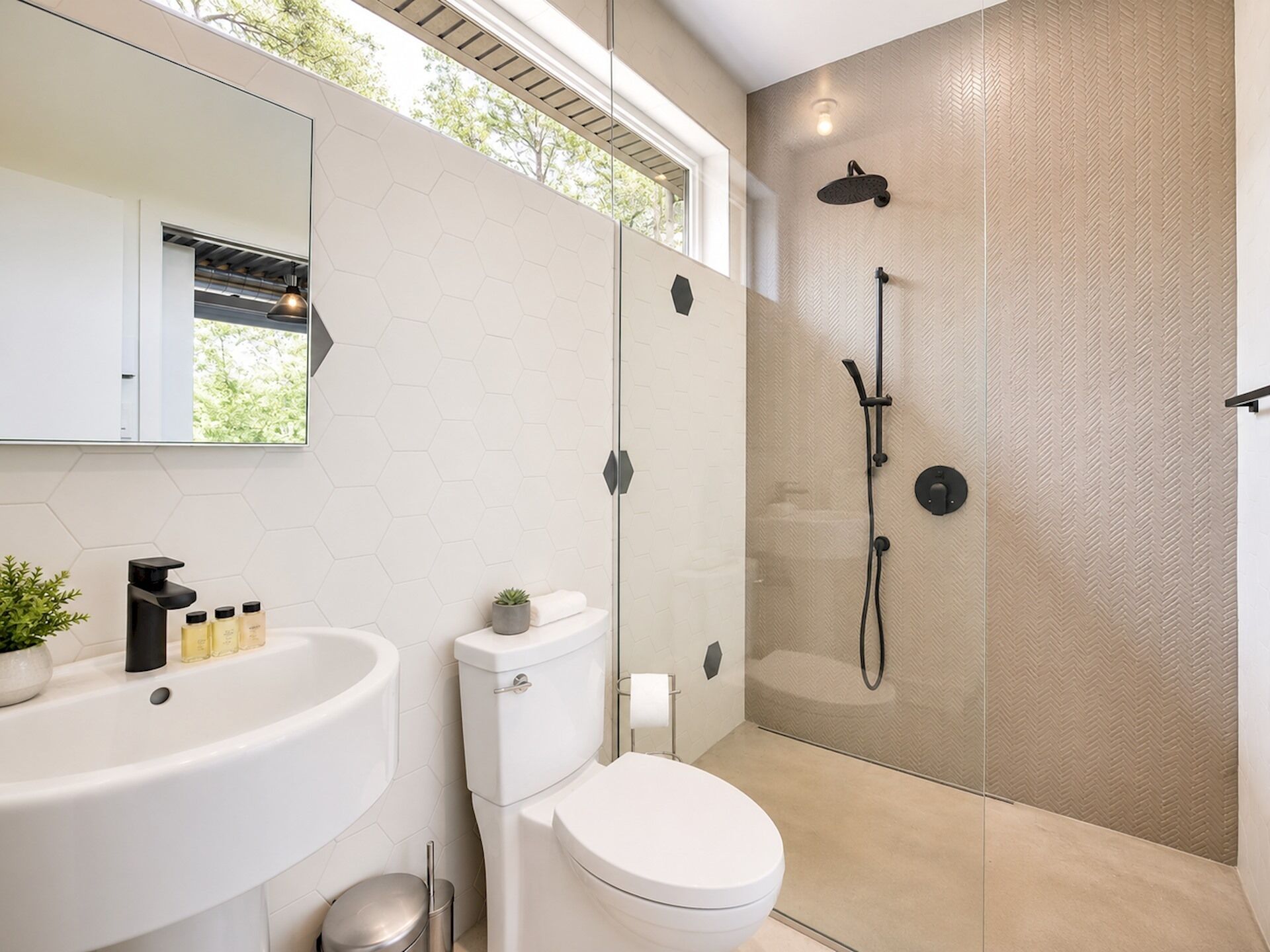 A modern bathroom with a shower, toilet, sink, and a mirror.