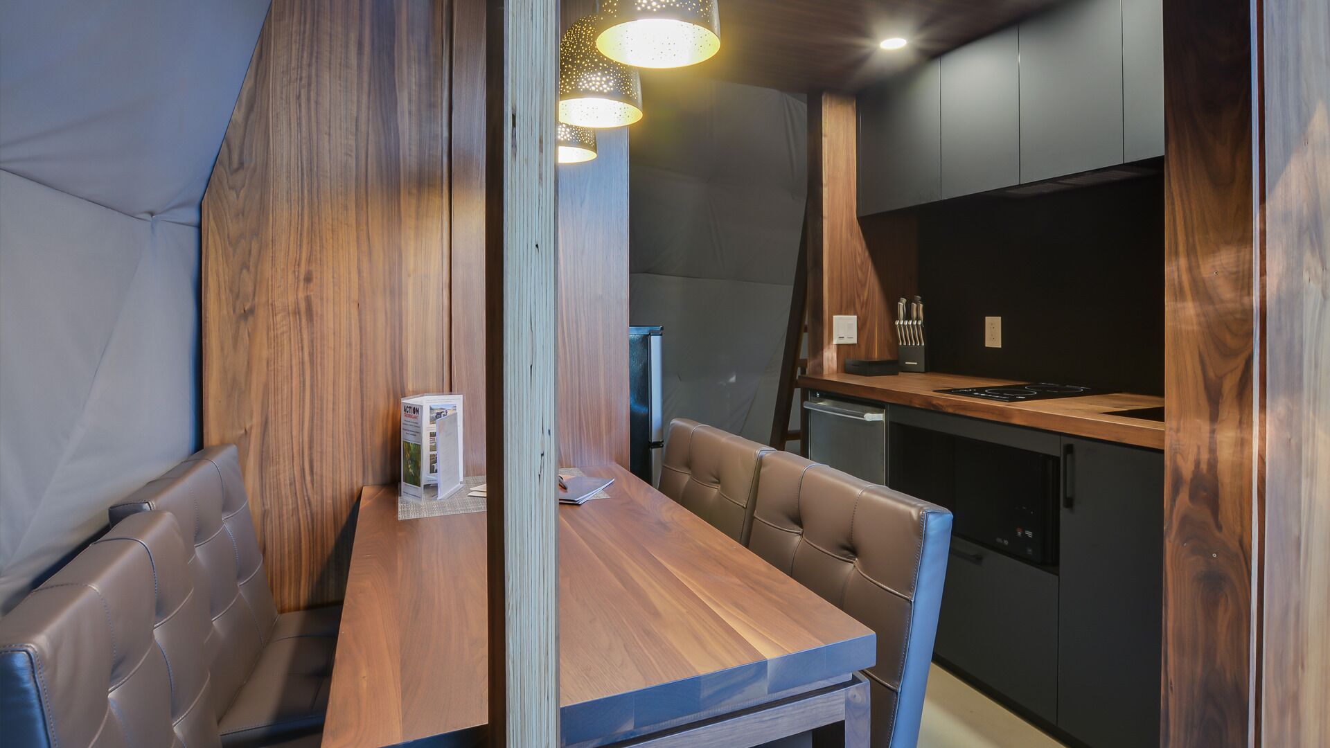 Uma cozinha compacta com mesa e banco de madeira, geladeira e pia.