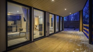 A modern building with large glass windows, a wooden deck, and a view of the outdoors.