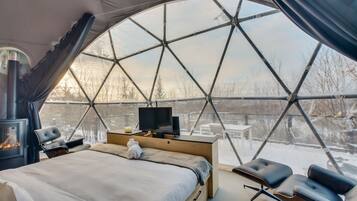A dome-shaped room with a bed, a television, and a fireplace.