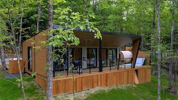 Una cabaña con terraza, ventanas amplias y un espacio exterior cubierto.