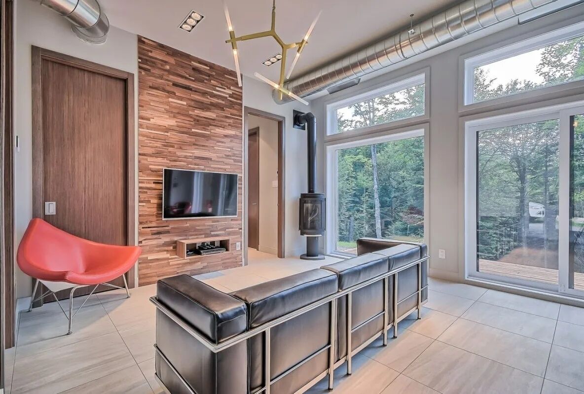 Un salon moderne avec un téléviseur, une cheminée et une grande fenêtre.