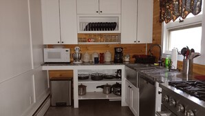 Eine moderne Küche mit weißen Schränken, einer Mikrowelle, einer Kaffeemaschine und einem Herd.