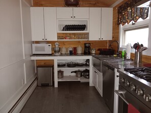 A modern kitchen with white cabinets, a microwave, a coffee maker, and a stove.
