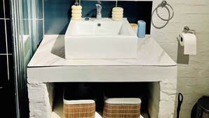 Ein Badezimmer mit einem weißen Waschbecken, einem Spiegel und zwei Korbwannen unter der Ablagefläche.