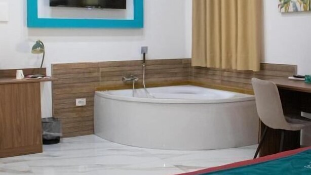 A modern bathroom with a bathtub, a vanity, and a television mounted on the wall. - Augustea Travel (San Marcellino)