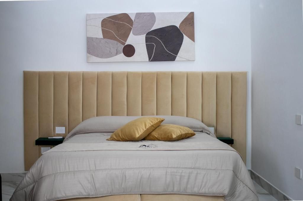A bed with a headboard, a pillow, a bedside table, and a wall-mounted abstract art piece.